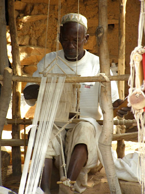 Man weaving Bogolan cloth on narrow loom